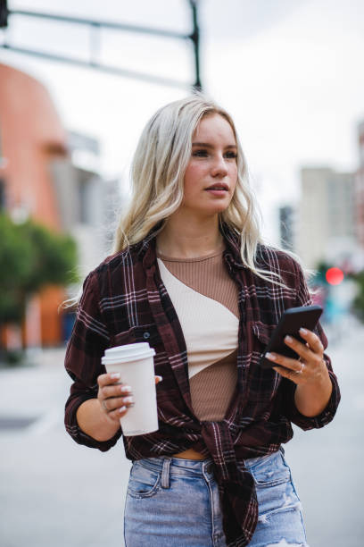 istock Young woman walking down the street, using smart phone 1748165960