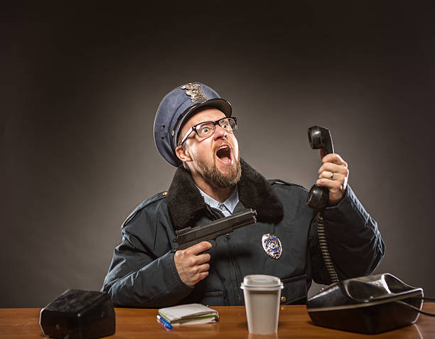 jefe de policía con un arma apuntando en el receptor de teléfono - desk police police station humor fotografías e imágenes de stock