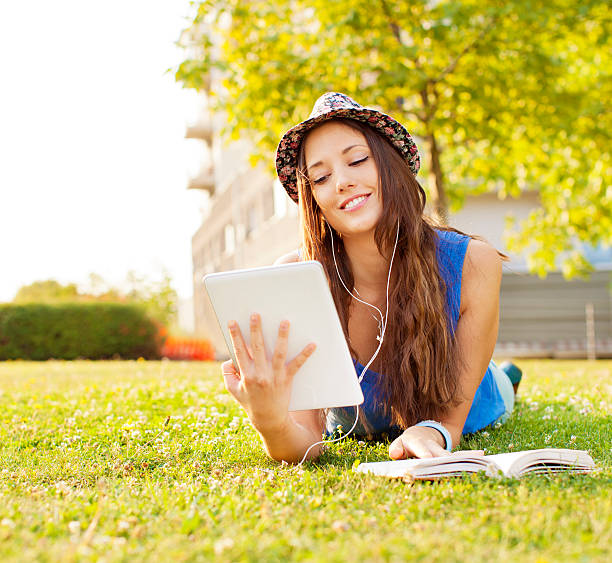 istock Happy Young Woman lying on grass and using digital tablet 174816980
