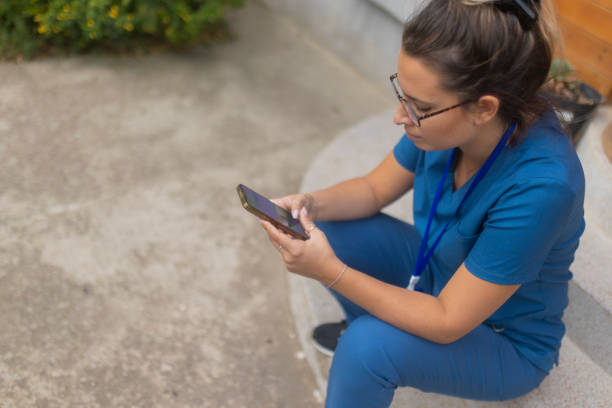 istock A medical worker is sitting on the steps in the yard, resting and using a mobile phone 1748173358