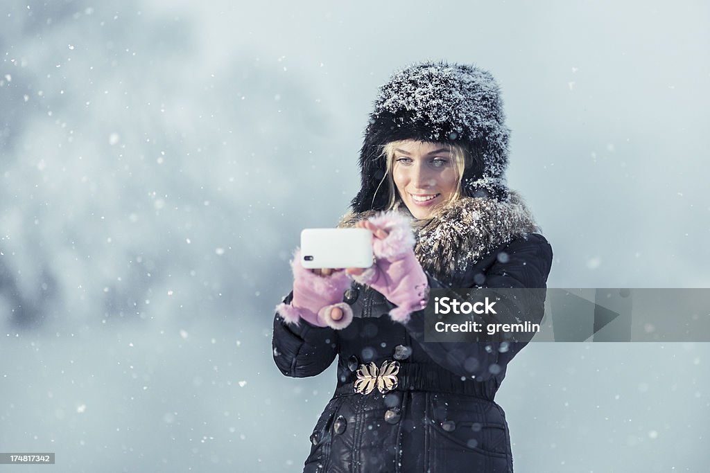 Jeune femme en plein air de prendre une photo à la neige sur une journée d'hiver - Photo de A la mode libre de droits