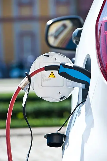 Photo of charge white electric car - view from behind