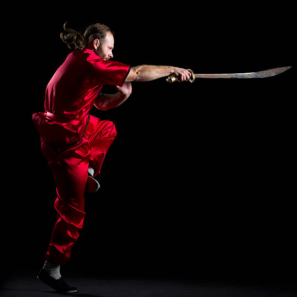 шаолинь кунг-фу борьбе с позиции с dao меч на черный - wushu skill action aggression стоковые фото и изображения