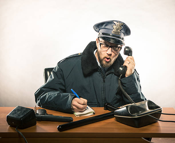 jefe de policía por teléfono en su escritorio - desk police police station humor fotografías e imágenes de stock