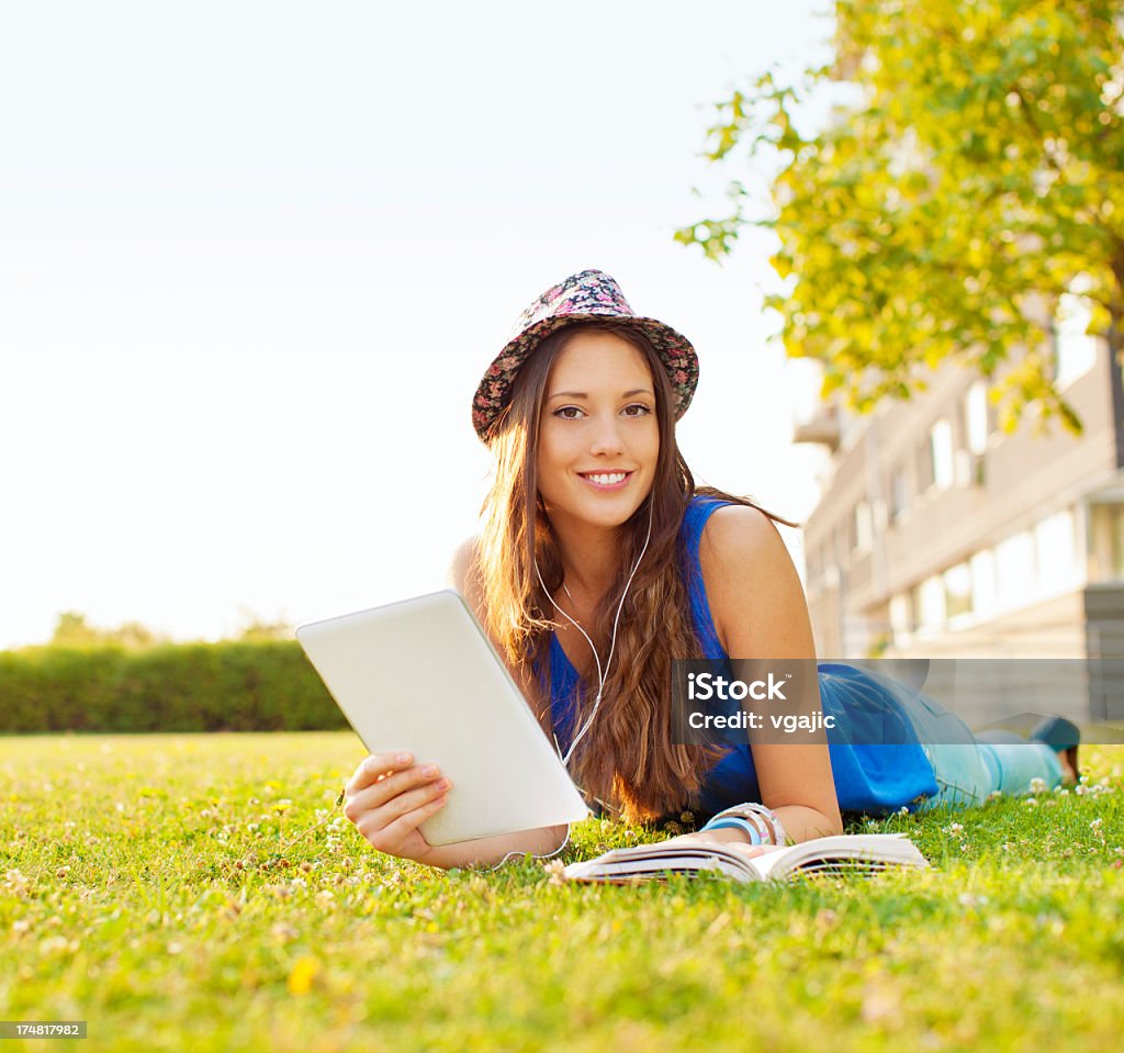 행복한 젊은 여자 라잉 on 잔디 및 디지털 타블렛을 잡고 있습니다. - 로열티 프리 공원 스톡 사진