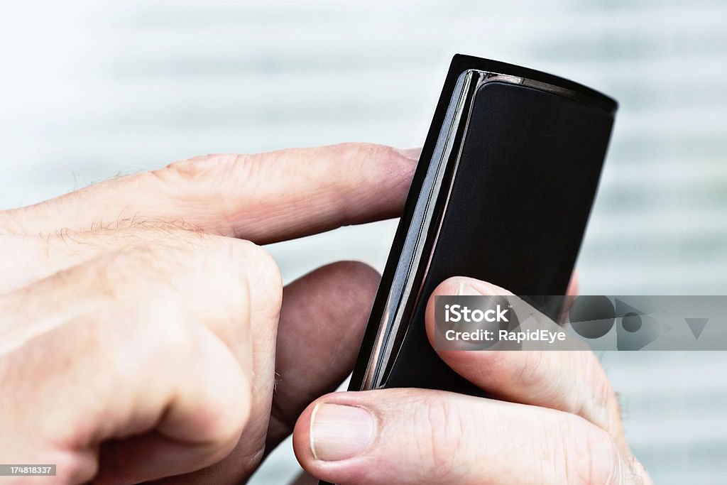 Close-up of male hands using mobile phone indoors "A man's hands tap on a cellphone, in close up, possibly texting." Blank Stock Photo