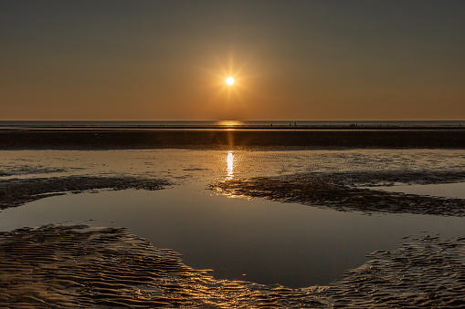 Looking out over Formby beach at low tide, with the sun setting over the sea