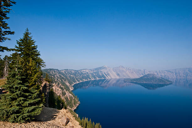 Crater Lake and Wizard Island in the Morning Crater Lake exists in the blown-out caldera of a once mighty volcano known as Mount Mazama. This view of the lake and Wizard Island was taken from the Garfield Peak Trail in Crater Lake National Park, Oregon, USA. jeff goulden crater lake national park stock pictures, royalty-free photos & images