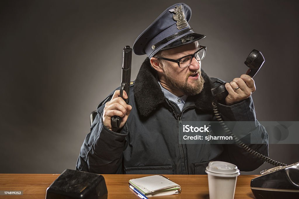 Commissario di polizia di parlare al telefono con pistola in mano - Foto stock royalty-free di Adulto
