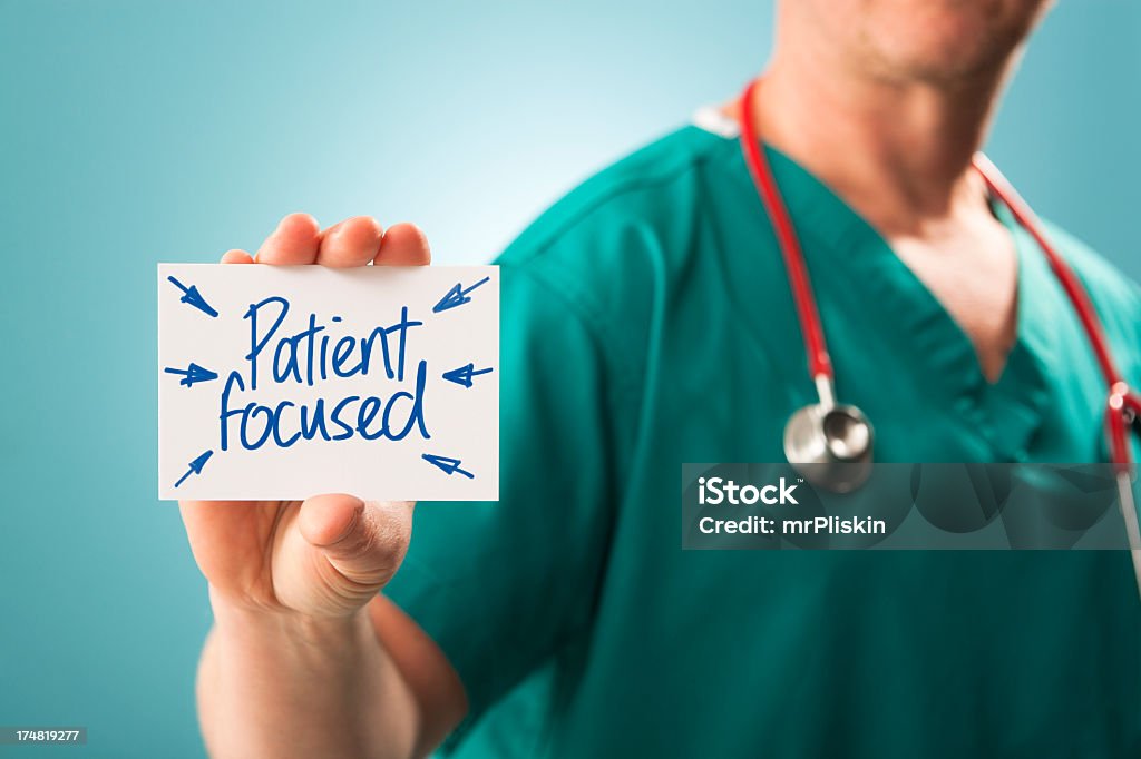 Patient focused The phrase 'Patient focused' written on white card held by a doctor/surgeon. Shallow depth of field, focus on the card and fingertips.  Agreement Stock Photo