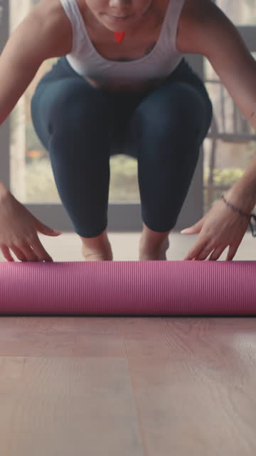 Woman, roll yoga mat and ready on floor for exercise, training or wellness with gym, class and health. Person, prepare and workout with pilates, zen or chakra with fitness, body and vision in home