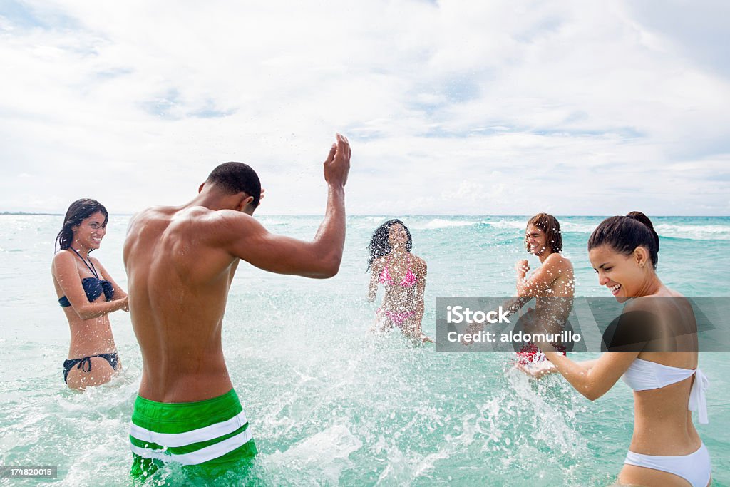 Happy friends splashing water to each other Happy friends splashing water to each other in the ocean 20-29 Years Stock Photo