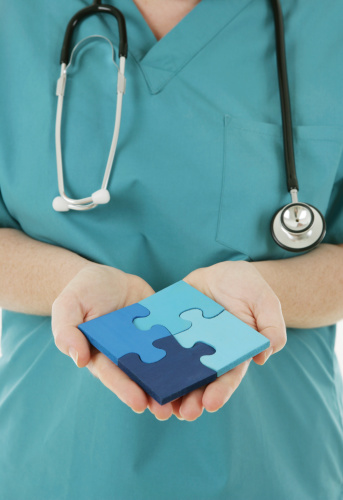 A nurse in scrubs holding a jigsaw puzzle.