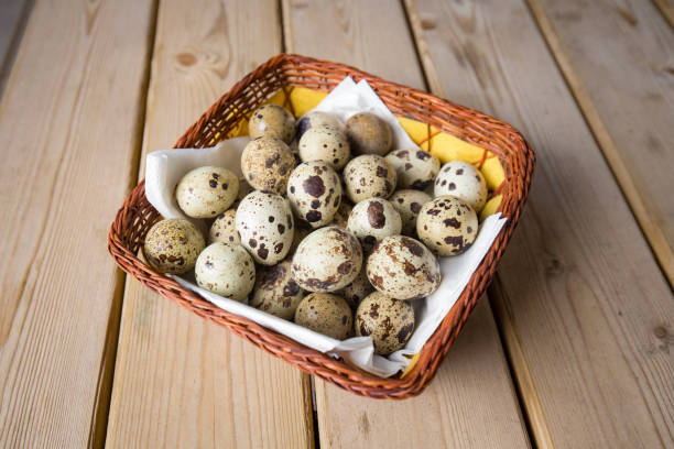 Arrange quail eggs in a straw basket on a wooden table.