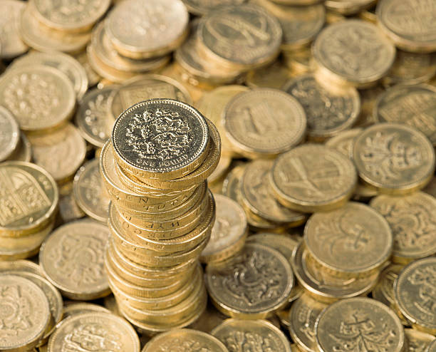 Pound Coin Stack A stack of UK pound coins rising from a defocussed background of pound coins. three lions england stock pictures, royalty-free photos & images