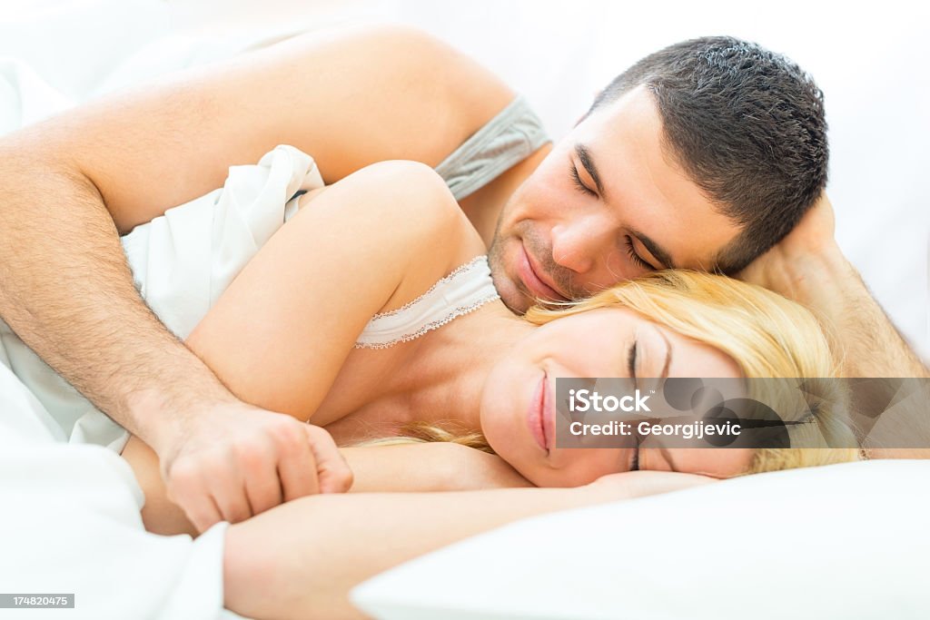 Giovane coppia sdraiata a letto - Foto stock royalty-free di Abbigliamento casual