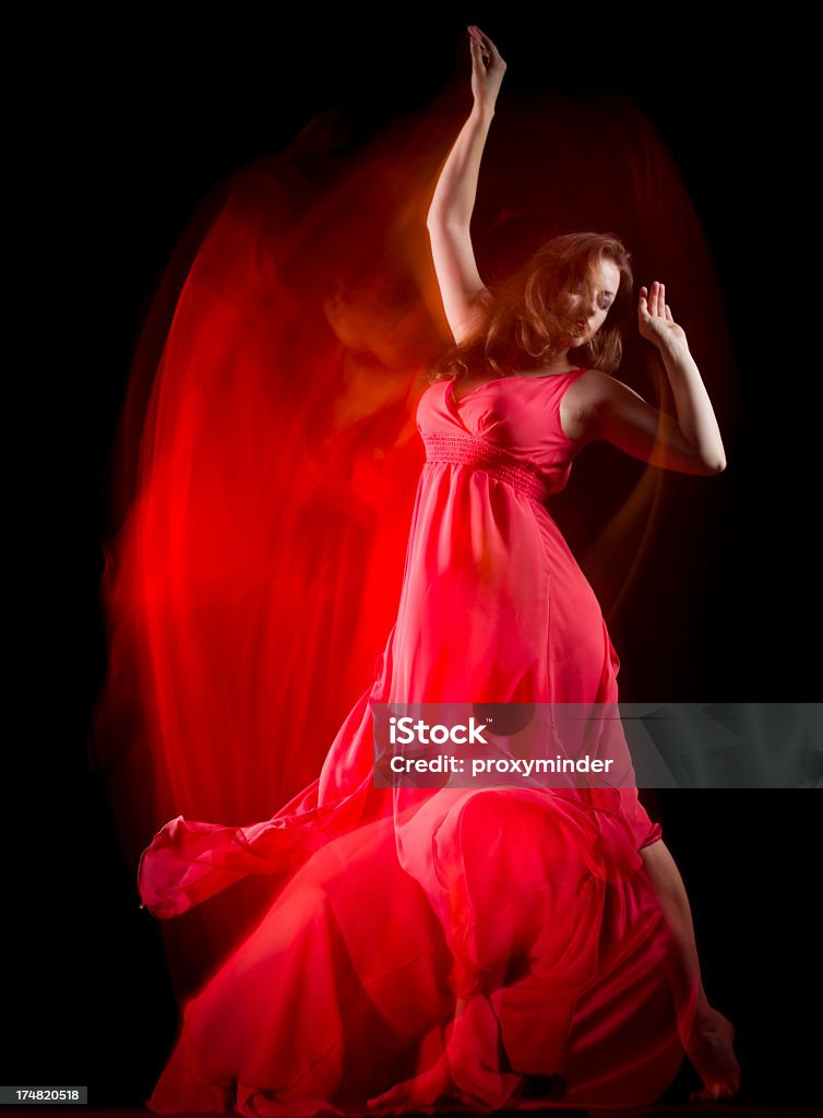 Female Dancer in red dress build patterns on black Dancer patterns on black background, Long Exposure Blurred Motion Stock Photo