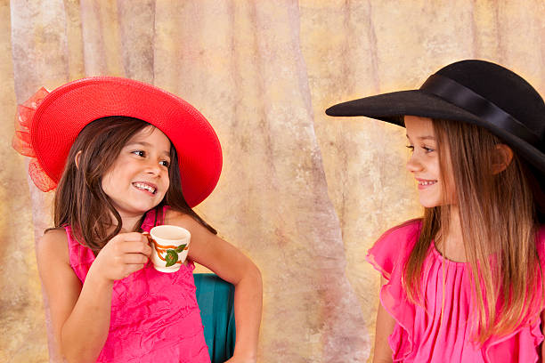 dos niños caucásicos niñas 7-8, juegan sombreros teacup - tea party dressing up little girls hat fotografías e imágenes de stock