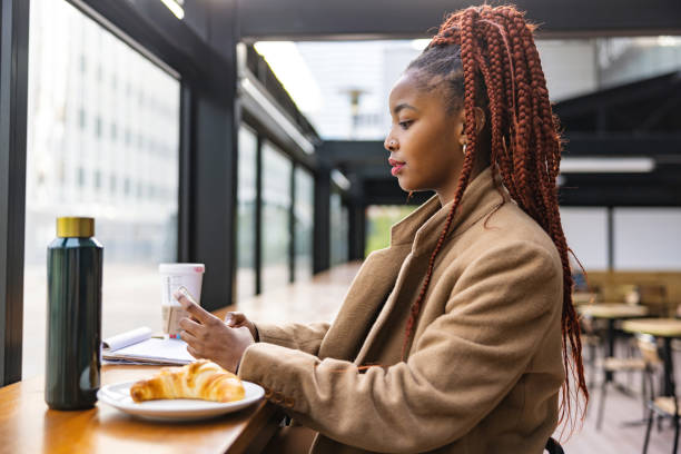 hermosa joven africana usando el teléfono en una cafetería - croissant telephone coffee shop on the phone fotografías e imágenes de stock