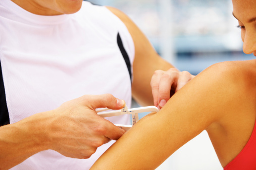 Cropped image of a fitness instructor using callipers  on a client's arm to measure body fat