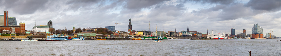 Panoramic aerial view over the rooftops of Hamburg, from the copper tower of Hauptkirche Sankt Michaelis, St Michael’s Church, past the high rises of St. Pauli to the busy cranes of the Port of Hamburg and blue waters of the Elbe, Germany.