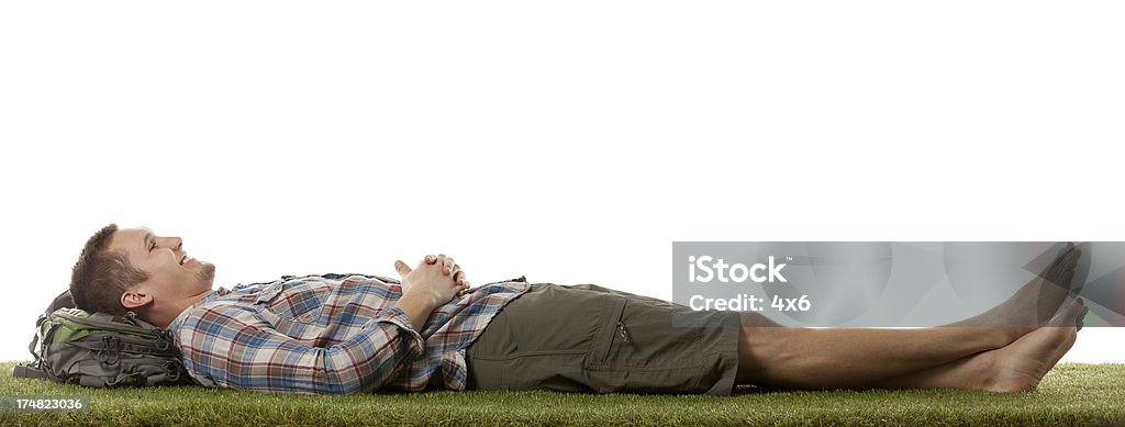 Uśmiech człowiek leżenie na trawie - Zbiór zdjęć royalty-free (Leżeć)