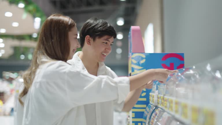 Couple using a Gashapon capsule toy vending machine