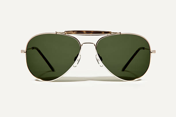 Pair of Tinted lens avaitor sunglasses A pair of gold rimmed aviator style sunglasses.  Lens tint is slightly green. aviator glasses stock pictures, royalty-free photos & images