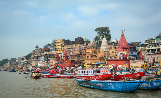 Varanasi, India - Jul 12, 2015. View of the riverbank of Ganges at sunny day in Varanasi, India. Varanasi draws Hindu pilgrims who bathe in the Ganges River sacred waters.