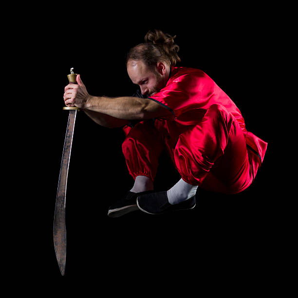 шаолинь кунг-фу борьбе с позиции с dao меч в midair - wushu skill action aggression стоковые фото и изображения