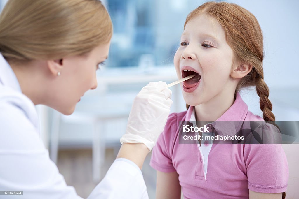Doctor examining child Female doctor examining child's throat at clinic 8-9 Years Stock Photo