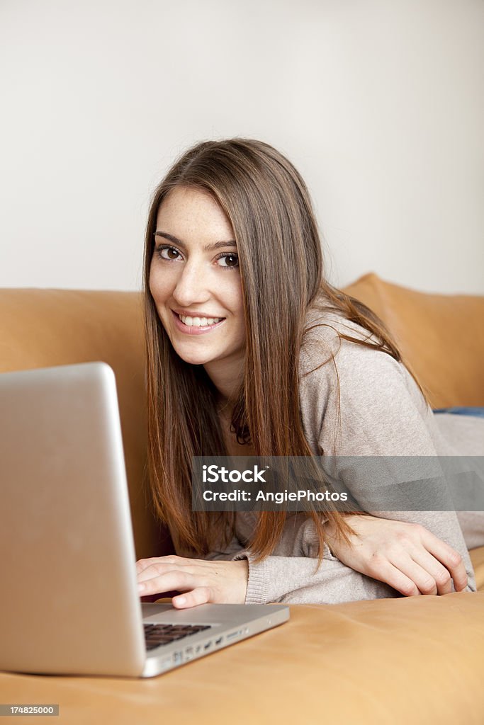 Молодая женщина с ноутбуком на диване - Стоковые фото Беспроводная технология роялти-фри