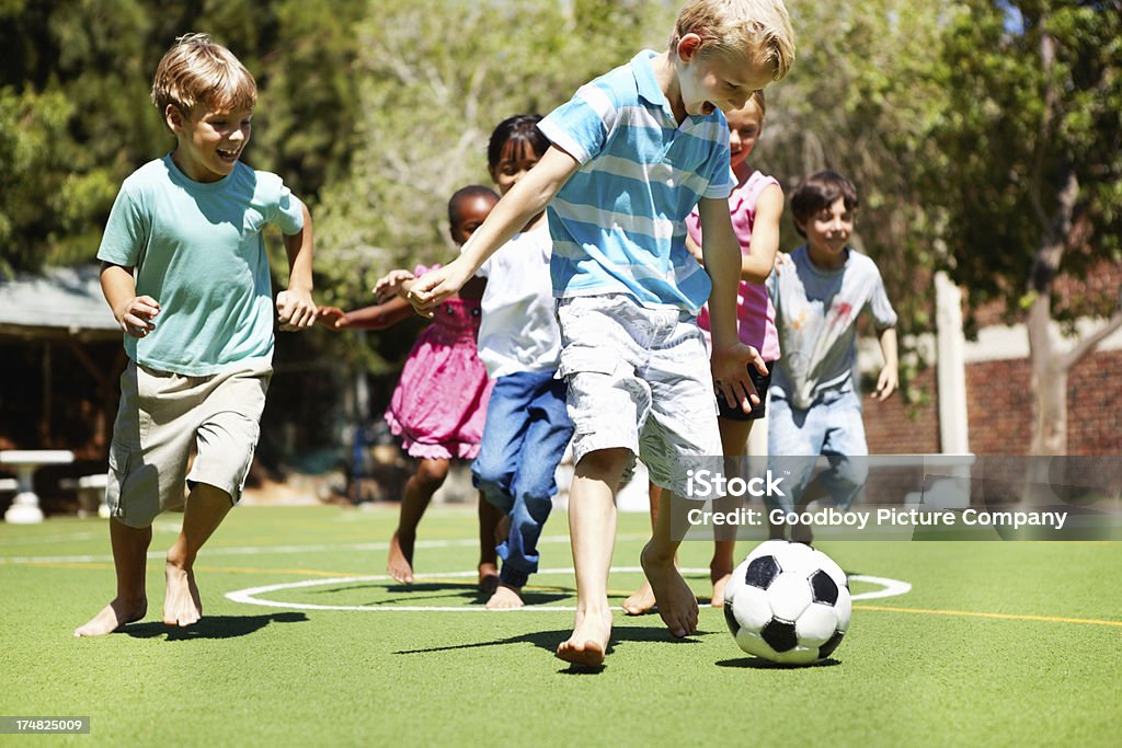 Młody chłopiec Gra futbolu ze znajomymi - Zbiór zdjęć royalty-free (Boisko)