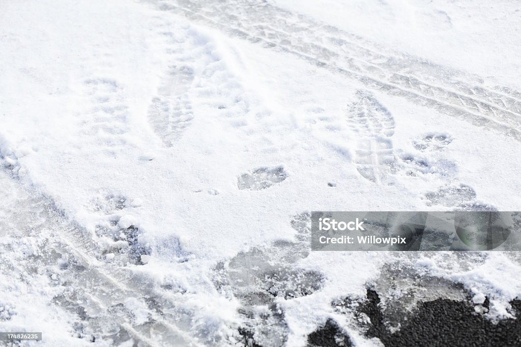 Abstract Tracks and Prints in Driveway Snow Abstract background of walking people foot prints, running dog paw prints, and rolling car tire tracks - all coming or going in different directions - on a winter snow-covered asphalt driveway. Abstract Stock Photo