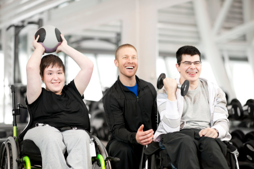 Young male and female with disabilities working out with trainer.