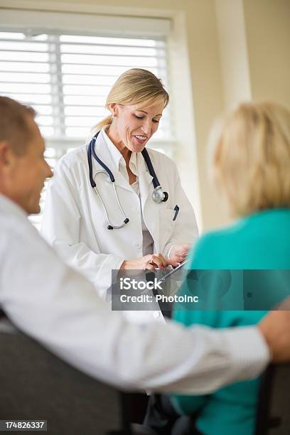 Arzt Mit Digitalen Tablet Mit Paar Sitzen In Den Vordergrund Stockfoto und mehr Bilder von Arzt
