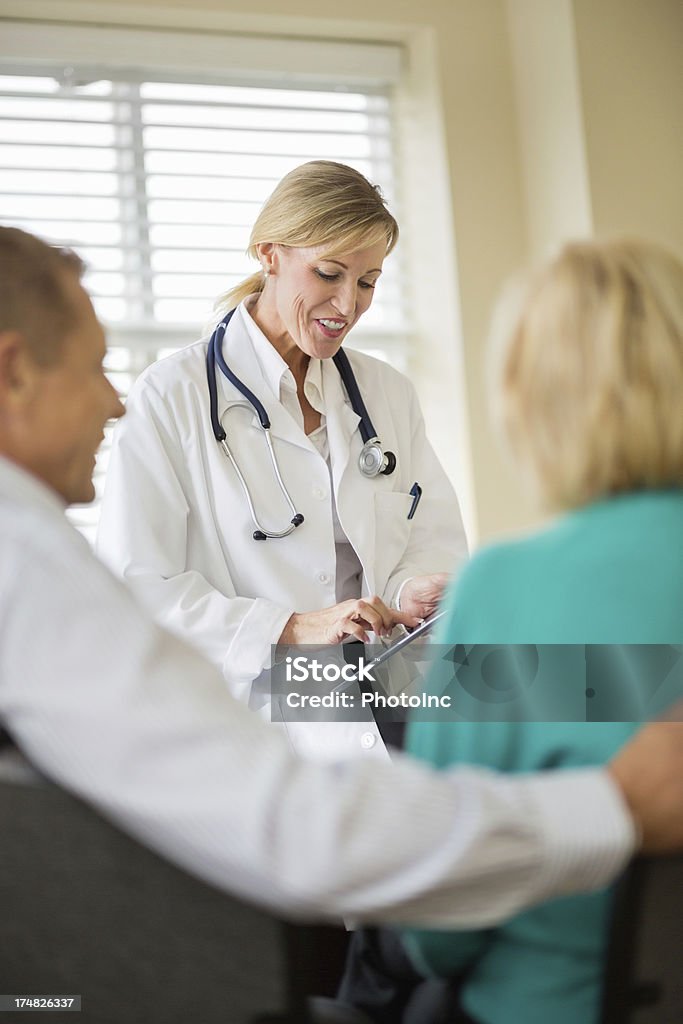 Doctor usando tableta Digital con pareja sentada en primer plano - Foto de stock de Doctor libre de derechos