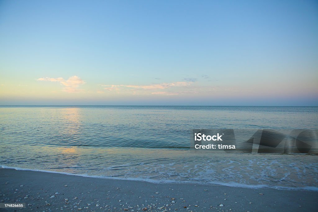 Empty beach with clear subtropical waters "Early morning delight in Sanibel Island, Florida:  glowing sky, endless beach, a horizon free of distractions and that glorious blue-green subtropical water warm enough to swim in even in the winter months." Backgrounds Stock Photo