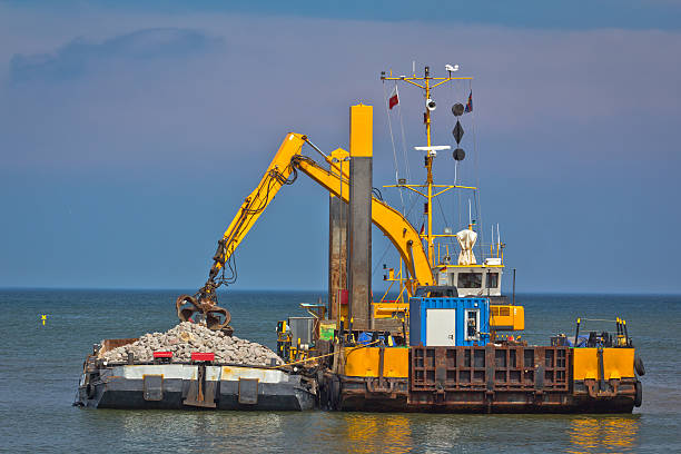 industrial lastkahn mit einem excavator auf das meer - industrial ship earth mover barge yellow stock-fotos und bilder