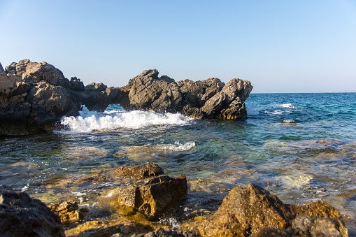 Crystal water and waves on rock coastline at small harbor of Kos, Dodecanese, Greece
