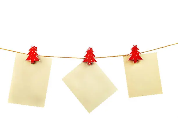 Blank cardboard pieces - cut like old photographs - hanging on clothesline with christmas tree pegs isolated on white