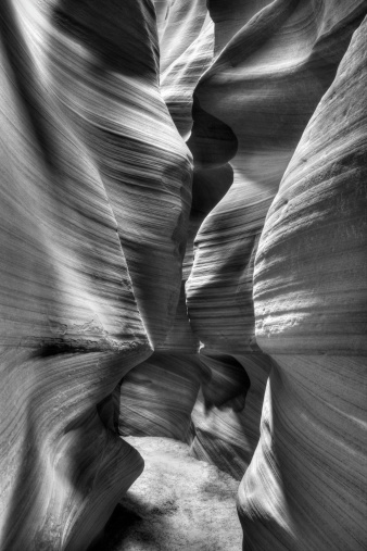 Antelope slot canyon sandstone textures created by years of erosion. Black and white vertical landscape.