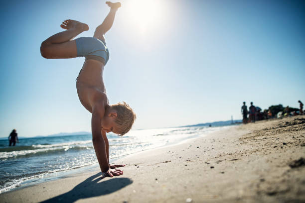 Little boy aged 8 is playing on the beach. The boy is doing a handstand. Summer sunny day in Tuscany, Italy.Shot with Nikon D810