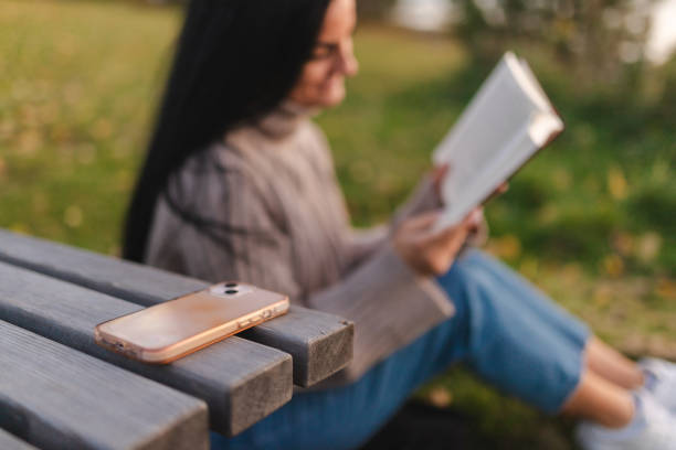 istock Smart phone and a girl reading in the background 1748290101