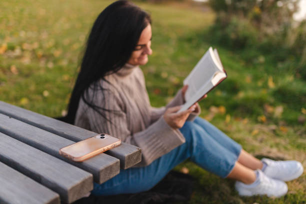 istock Smart phone and a girl reading in the background 1748290110