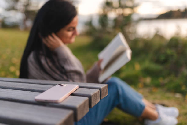 istock Smart phone and a girl reading in the background 1748290119