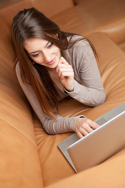 istock Young woman with laptop on sofa 174829032