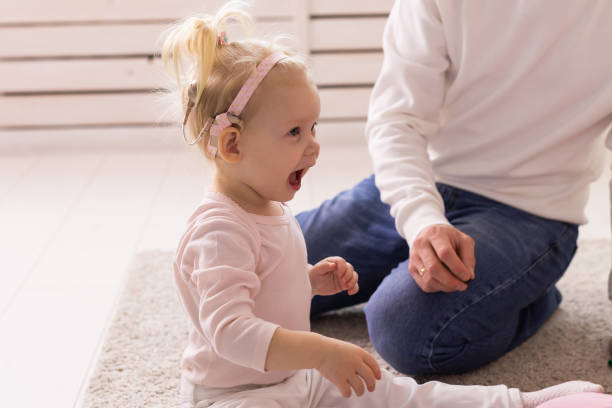 Baby with cochlear implants having fun at home. Deafness and medical technology