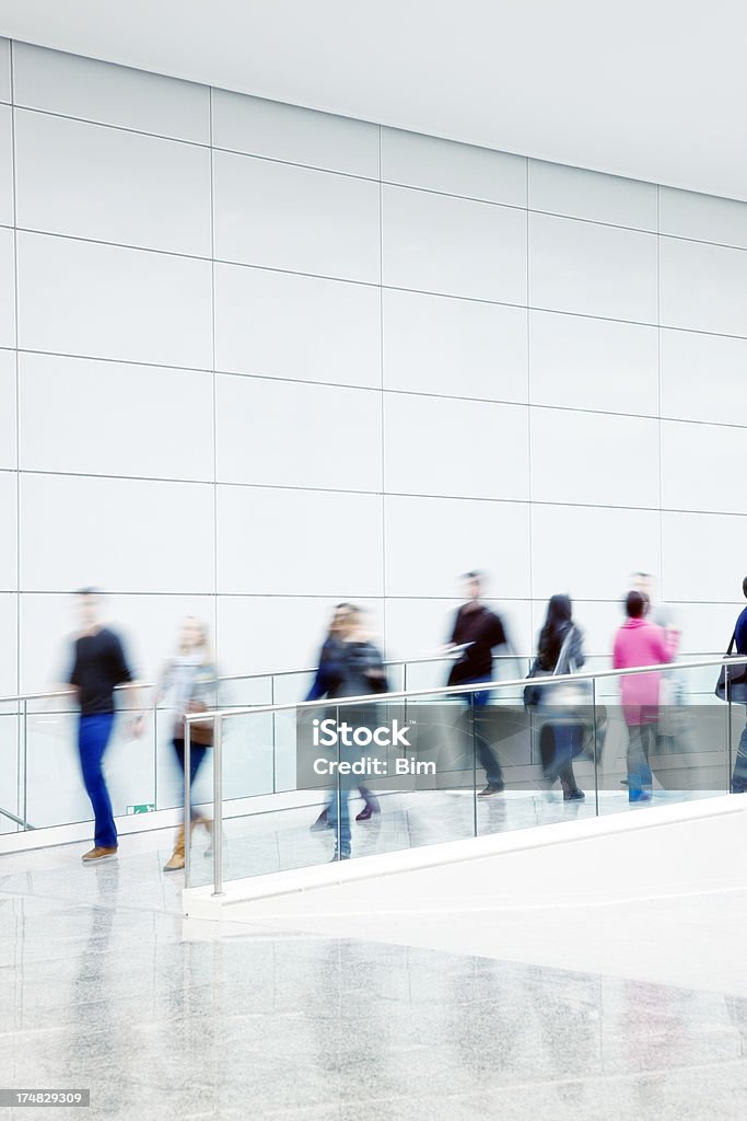 Motion Blurred People Walking Indoors blurred pedestrians rushing in modern interior, Railing Stock Photo