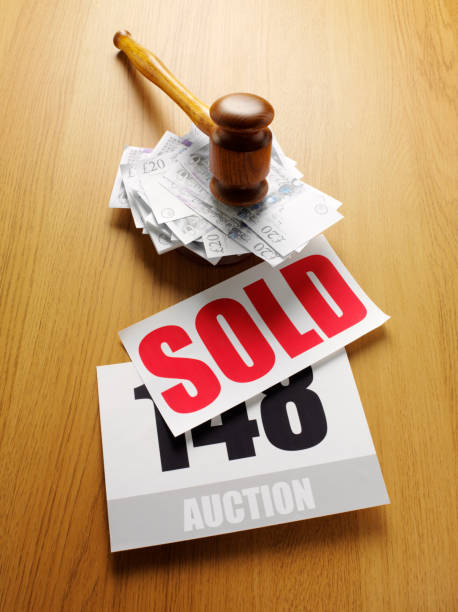 Sold at Auction with British Twenty Pounds and a Mallet "A pile of British twenty pound notes on a wooden table under a wooden auction mallet, with a red sold sign and auction paddle Click on the link below to see more of my business and auction images" twenty pound note stock pictures, royalty-free photos & images